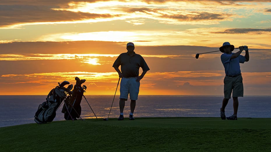 GolfAhoy Hawaii Golf Cruises photo view at sunset showing two golfers with brilliant pacific sunset in the background.