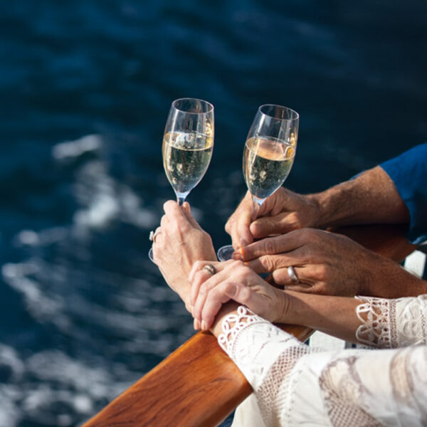 50th wedding anniversary couple celebrating with glasses of champagne on a GolfAhoy Hawaii golf cruise.